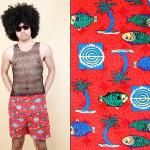 May include: Red swim trunks with a colorful pattern of fish, palm trees, and targets. The trunks have a black elastic waistband and a drawstring.