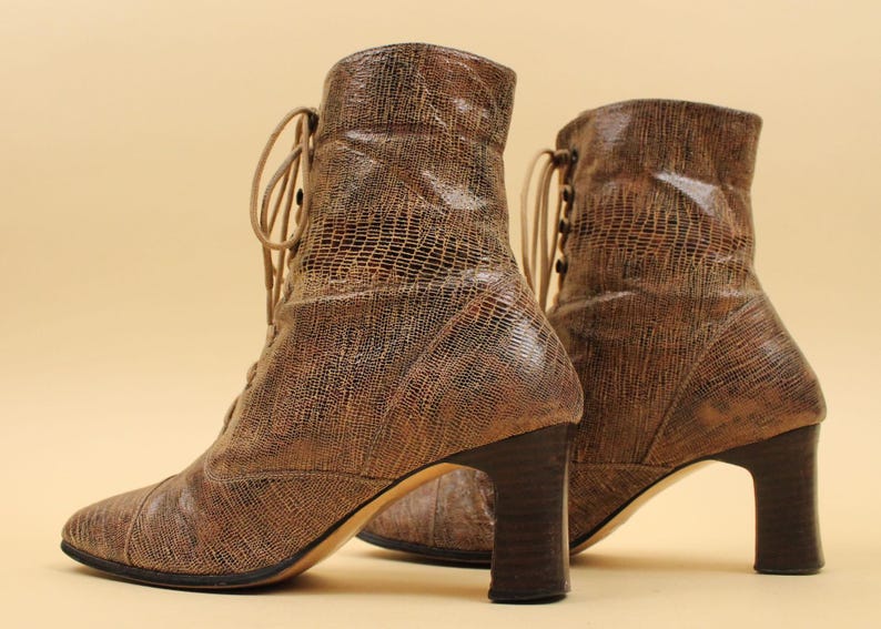 May include: A pair of brown leather ankle boots with lace-up fronts and block heels. The boots have a textured, snakeskin-like pattern.