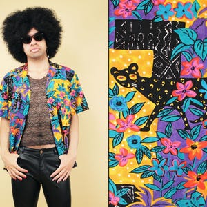 Peut inclure: Une chemise boutonnée colorée avec un imprimé tropical représentant un panthère noire, des perroquets et des fleurs. La chemise a des manches courtes et une coupe décontractée.