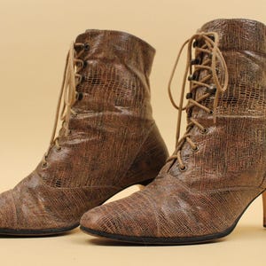 May include: A pair of brown leather lace-up boots with a textured finish and a block heel.
