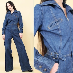 Op de afbeelding: Een blauwe denim jumpsuit met een rits, lange mouwen en wijde pijpen. De jumpsuit heeft een kraag en een riem.