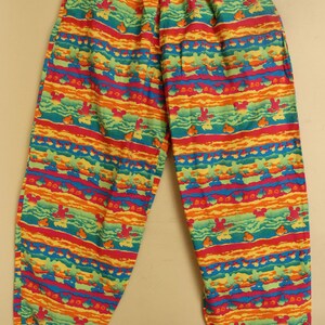 May include: Multicolored pants with a striped pattern featuring a repeated design of Mickey Mouse heads. The pants have an elastic waistband and a relaxed fit.
