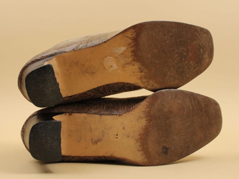 May include: A pair of brown woven heeled shoes with a brown leather sole. The shoes are stacked on top of each other.