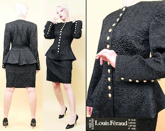 May include: A black peplum suit with gold buttons. The suit is made of a textured fabric and has a fitted silhouette. The jacket has a peplum hem and the skirt is knee-length. The suit is labeled "Louis Féraud" and has size tags in French, American, and British sizes.