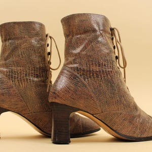 May include: A pair of brown leather ankle boots with lace-up fronts and chunky heels. The boots have a textured, snakeskin-like pattern.
