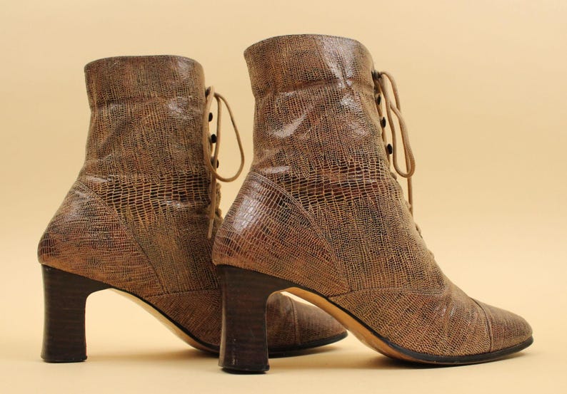 May include: A pair of brown leather ankle boots with lace-up fronts and chunky heels. The boots have a textured, snakeskin-like pattern.