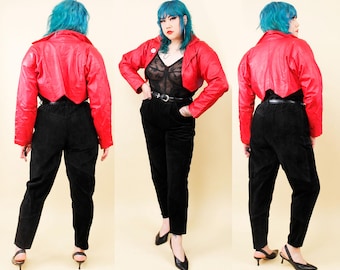 Könnte beinhalten: Eine rote, kurze Lederjacke mit spitzen Kragen und langen Ärmeln. Die Jacke wird über einem schwarzen Spitzenoberteil und einer schwarzen Hose getragen.