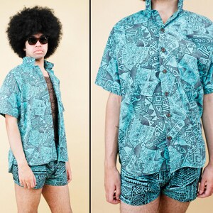Puede incluir: Una camisa abotonada turquesa y gris estampada y pantalones cortos a juego. La camisa tiene mangas cortas y cuello. Los pantalones cortos tienen cintura elástica. El estampado presenta formas geométricas. El conjunto es de estilo vintage.