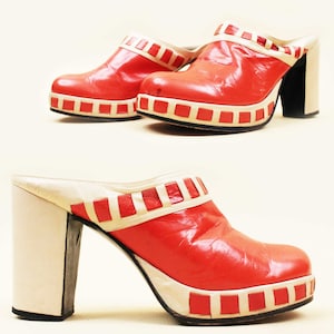 May include: A pair of red platform clogs with white trim. The clogs have a chunky heel and a square toe.