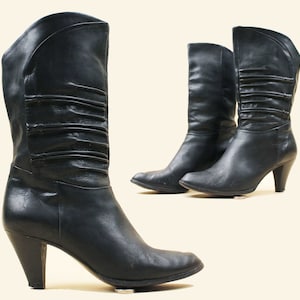 May include: A pair of black leather heeled boots with a pointed toe and a fold-over detail on the shaft.