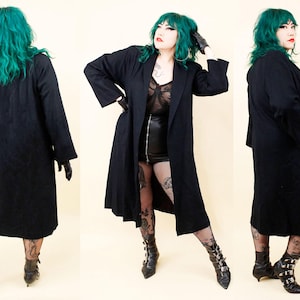 May include: A long, black coat with a classic lapel design. The coat is shown from multiple angles, showcasing its length and fit. The model is wearing black gloves and boots. The coat appears to be made of a heavy fabric, suitable for cooler weather.