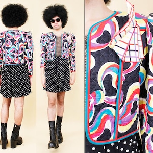 May include: A vintage quilted jacket with a vibrant abstract pattern in red, blue, yellow, and purple. The jacket has a black base with a red and blue trim. The model is wearing a black and white polka dot skirt and black boots.