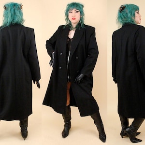 May include: A long, black, double-breasted coat featuring structured shoulders, a notched lapel collar, and long sleeves. The coat is shown from the back, front, and side angles, displaying a straight, knee-length silhouette with a smooth finish.
