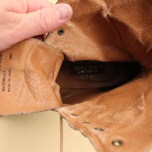 May include: Inside view of a brown leather boot with a lace-up closure. The boot is lined with a soft brown fabric and has a label that reads "Balance Man Made Materials Made in Korea".
