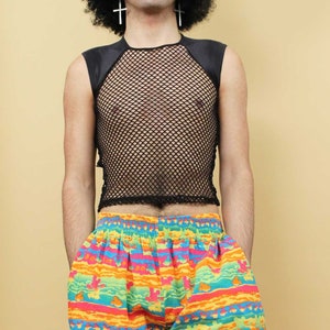 May include: A person wearing a black mesh tank top with a black satin trim and colorful striped pants with a pattern of cartoon characters.