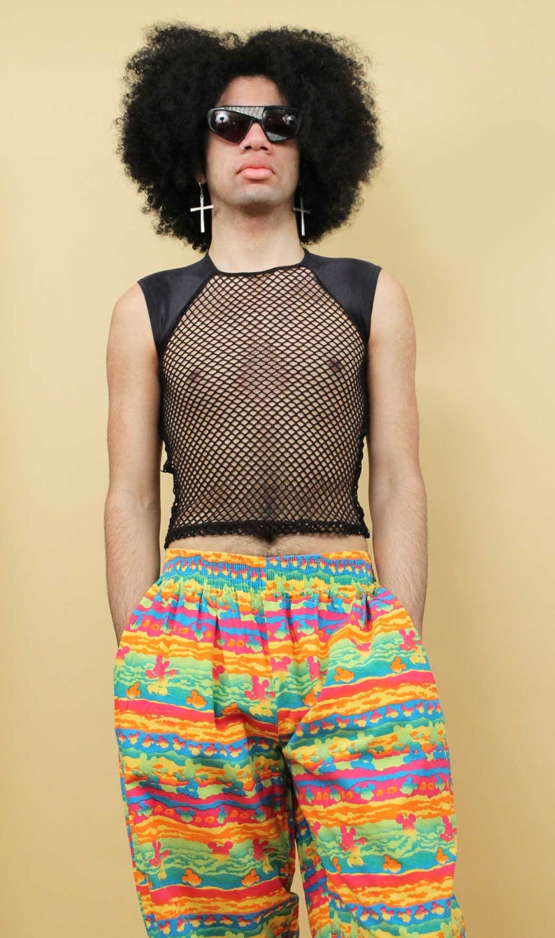 May include: A person wearing a black mesh tank top with a black satin trim and colorful striped pants with a pattern of cartoon characters.