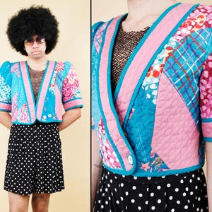 May include: A colorful patchwork jacket with a V-neck design. The jacket features a mix of blue, pink, and floral patterns, with a black and white polka dot skirt. The jacket has short sleeves and a quilted texture.