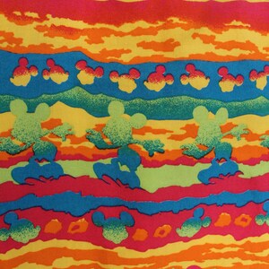 May include: A colorful fabric with a repeating pattern of Mickey Mouse silhouettes. The fabric features a striped design with alternating bands of red, orange, yellow, green, and blue. The Mickey Mouse silhouettes are in various shades of green, orange, and red.