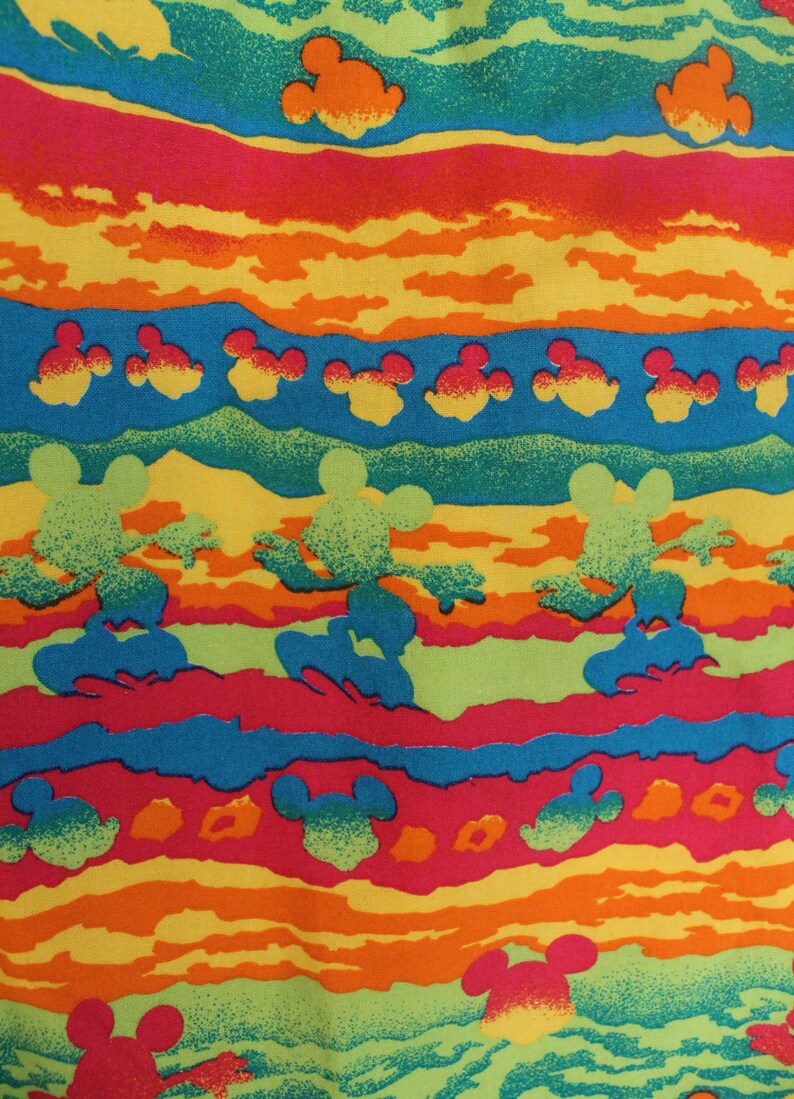 May include: A colorful fabric with a repeating pattern of Mickey Mouse silhouettes. The fabric features a striped design with alternating bands of red, orange, yellow, green, and blue. The Mickey Mouse silhouettes are in various shades of green, orange, and red.