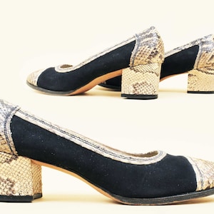 May include: A pair of black suede pumps with snakeskin heels. The shoes have a pointed toe and a low heel.
