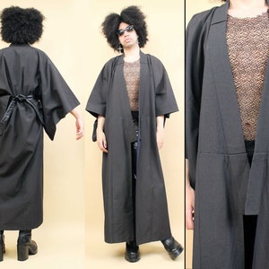 May include: A long black kimono with a wide collar and long sleeves. The kimono is tied at the waist with a black belt. The kimono is made of a soft, flowing fabric.