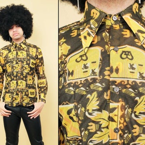 Puede incluir: Una camisa de manga larga con un patrón geométrico en tonos amarillos y marrones. La camisa tiene un cuello puntiagudo y un cierre de botones.