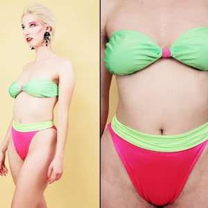 Op de afbeelding: Een groen en roze tweedelig badpak. De bovenkant is een strapless bandeau-stijl en de onderkant is een hoge bikini-slip.