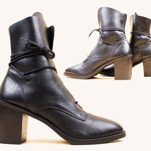 以下が含まれることがあります： 丸いつま先とブロックヒールを備えた黒いレザーアンクルブーツ。ブーツは足首の周りにレースアップのデザインとスタックヒールを備えています。ブーツはスタジオで表示されています。