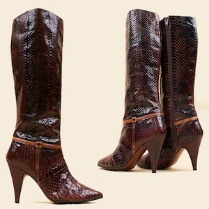 May include: A pair of brown snakeskin heeled boots with a buckle detail on the ankle.