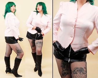 May include: A light pink blazer with shoulder pads and three buttons. The blazer is paired with a black leather skirt, black gloves, fishnet stockings, and black knee-high boots. The model has green hair.