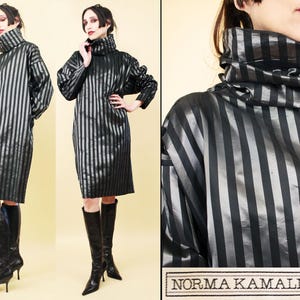 Może przedstawiać: Czarno-srebrna sukienka w paski z wysokim kołnierzem. Sukienka sięga do kolan i ma długie rękawy. Sukienka jest wykonana z jedwabistej tkaniny i ma delikatny połysk. Sukienka jest marki Norma Kamali.