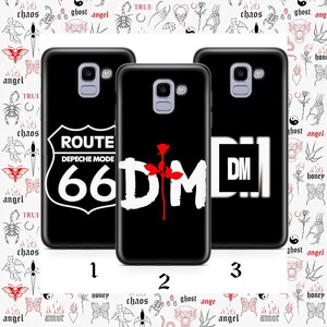 以下が含まれることがあります： 白と赤のグラフィックが施された黒い携帯電話ケース3つ。1つは「ROUTE DEPECHE MODE 66」の道路標識が特徴です。もう1つは赤いバラが付いた「DM」です。3つ目は白い四角の中に「DM」が表示されています。ケースには1、2、3と番号が付けられています。