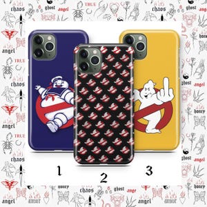 May include: Three phone cases with unique designs. One is navy blue with the Stay Puft Marshmallow Man, another is black with a repeating Ghostbusters logo, and the third is yellow with the Ghostbusters logo and a ghost giving the middle finger.