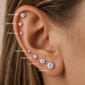 Peut inclure: Une collection de sept boucles d'oreilles à clous rondes et transparentes de tailles variées, étiquetées avec les mesures : 6,0mm-0,8ct, 5,0mm-0,5ct, 3,0mm-0,1ct, 2,0mm-0,03ct, 4,0mm-0,3ct, 6,5mm-1ct et 7,0mm-1,2ct. Chaque clou est serti.