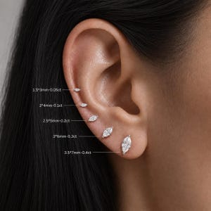 Peut inclure: Cinq boucles d'oreilles à clous en forme de marquise transparente disposées verticalement sur le lobe et le cartilage. Tailles indiquées : 1,5*3mm-0,05ct, 2*4mm-0,1ct, 2,5*5mm-0,2ct, 3*6mm-0,3ct et 3,5*7mm-0,4ct. Monture en métal argenté.
