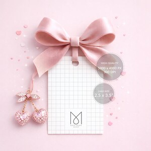 May include: A pink gift tag with a grid pattern, hanging from a large satin bow. The tag is adorned with a sparkling cherry charm. The card size is 2.5 x 3.5 inches. The background is a soft pink.