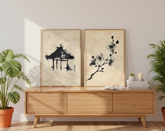 以下が含まれることがあります： 日本の水墨画をあしらった2つの額入りアートプリント。1つは塔、もう1つは花の咲く枝を描いています。プリントは木製のフレームに入っており、明るい木製のキャビネットの上に置かれています。植物や装飾がシーンを完成させています。