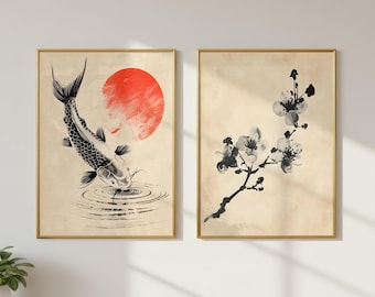 以下が含まれることがあります： 2つの額入りアートプリント。1つは、赤い太陽を背景に、水中で泳ぐ白黒の鯉を描いています。もう1つは、白黒の桜の枝を示しています。どちらのプリントも金色のフレームに入っています。