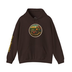 May include: A dark brown hoodie with a front pocket and a drawstring hood. The front features a circular graphic with a landscape scene and the text "Love is Everywhere." The left sleeve has the text "Love is Everywhere" in yellow.