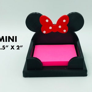 May include: Black desk organizer shaped like a mouse with a red bow and white polka dots. The organizer holds a stack of pink sticky notes. The text "MINI 1.5" X 2"" is visible.
