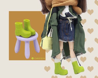 May include: A green doll wearing a green jacket, a brown scarf, a white shirt, a blue denim skirt, and green boots. The doll is holding a yellow bag. The doll is sitting on a purple stool with a pair of green boots on top of it. The text "SUGAR BOOTS CUTE BABY 2021" is at the top of the image. The text "sugar SUPER AGENT" is in the top right corner of the image.