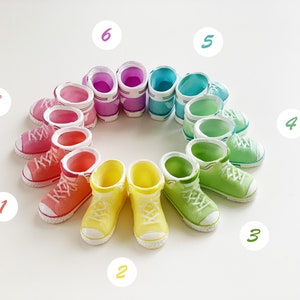May include: A circle of colourful planters shaped like trainers. The planters are arranged in a rainbow pattern, starting with pink and ending with green. Each planter has a number on it, from 1 to 7.