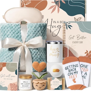 May include: A gift set containing a light blue textured blanket with a white ribbon, a beige sleep mask, a white mug with "hug in a mug" text, a spiral notebook with "Get Better EVERY DAY" text, socks with "GETTING BACK ON MY FEET" text, a candle, a crochet heart plant, a bath bomb, and soap.