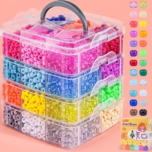 May include: A clear plastic bead organizer with a gray handle, filled with colorful beads in various shades of pink, blue, orange, yellow, green, and white. A small box of Pony Beads is visible on the right.