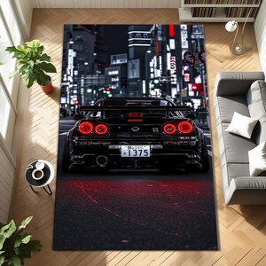 May include: Black car rug featuring a sports car with bright red taillights. The rug depicts a nighttime city scene with illuminated buildings and streets. The car's license plate reads "1375".