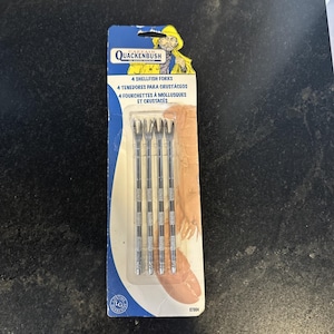 May include: A package of four stainless steel shellfish forks. The package has a blue and white design with the text "QUACKENBUSH" and "4 SHELLFISH FORKS". The forks are designed for eating shellfish and crustaceans.