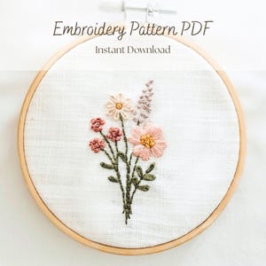 May include: An embroidery pattern PDF featuring a floral design. The design shows a bouquet of embroidered flowers in pink, peach, and cream, with green stems and leaves. The text "Embroidery Pattern PDF" and "Instant Download" are at the top.