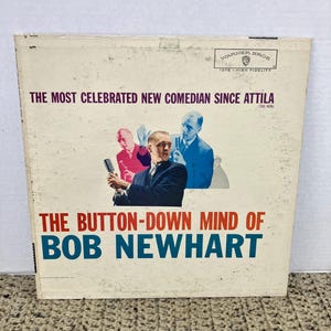 May include: Vintage vinyl record album cover for "The Button-Down Mind of Bob Newhart." The cover features a portrait of Bob Newhart with the text "The Most Celebrated New Comedian Since Attila" and "Warner Bros" logo.