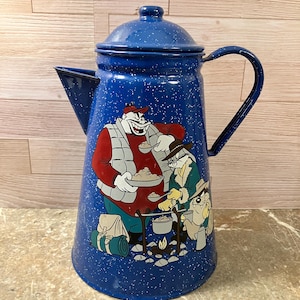 May include: A blue enamelware coffee pot with a white speckled pattern. The pot features a cartoon illustration of characters cooking over a campfire. It has a lid, spout, and a curved handle.