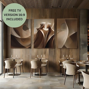 Puede incluir: Tres obras de arte abstractas enmarcadas en tonos marrones y beige cuelgan de una pared de madera. El arte presenta formas curvas y fluidas. El texto "FREE TV VERSION 16:9 INCLUDED" está en un círculo verde en la esquina superior izquierda. Mesas y sillas en primer plano.